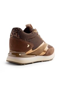 Baskets athlétiques marron avec une tige en mesh, des accents en suede, des détails métalliques dorés et une semelle épaisse avec une finition texturée.