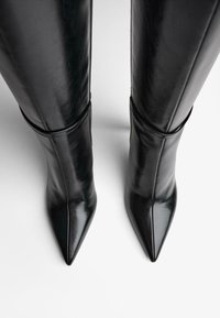 Cizme negre din piele până la genunchi, cu vârf ascuțit, textură netedă și gambă ajustată. Prezintă un design structurat fără elemente hardware vizibile.