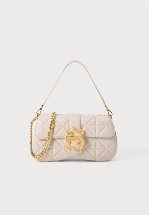 Bolso beis acolchado con una cadena de oro y un detalle de hardware dorado ornamentado en la parte frontal. El bolso tiene una forma estructurada y rectangular.