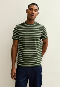 Camiseta de manga corta a rayas verdes con rayas horizontales blancas y un escote redondo, hecha de un material de algodón suave.