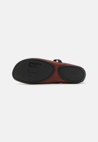 Zapato marrón con parte superior de suave ante y suela de goma. La parte inferior presenta surcos de tracción en negro y una marca grabada. Talla 38 indicada.