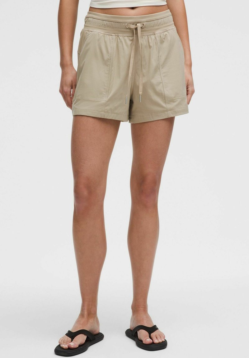 Beiga sportshorts med elastisk midja och dragsko, med två sidofickor och en strukturerad yta.