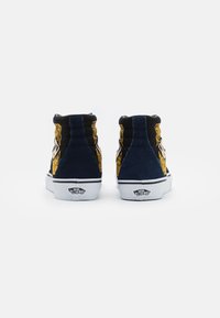 Baskets montantes en daim bleu marine et tissu noir, avec des détails brodés jaunes, des semelles en caoutchouc blanches et le logo Vans à l'arrière.