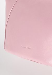 Borsa a tracolla rosa in pelle con una superficie liscia e una leggera lucentezza. Presenta dettagli di design curvi e il logo del marchio impresso sul davanti.