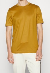 Kortärmad senapsgul t-shirt i mjuk bomull, med rund halsringning och enkel design med subtila sömdetaljer.