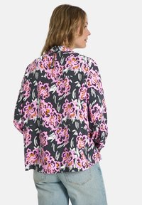 Floral blouse featuring a dark background with pink and white flowers. Loose fit with long sleeves and a small back keyhole detail.