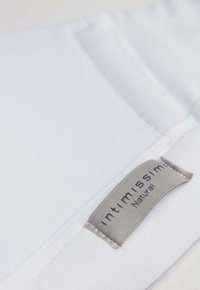 Vit tyg med en slät textur, med en grå etikett som säger "intimissimi" och "Natural" i svart, sydd vid kanten.