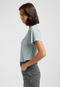 Camicetta a maniche corte azzurro chiaro realizzata in tessuto morbido con una vestibilità comoda. Presenta un collo rotondo e un logo discreto sul davanti.