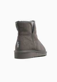 Botines de ante gris con un forro suave, suela de goma resistente y un parche con el logo en el costado. Textura suave y diseño de punta redondeada.