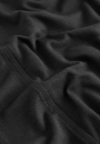 Black fabric with a smooth texture, featuring subtle wrinkles and a seam detail, highlighting its lightweight and stretchable quality.
