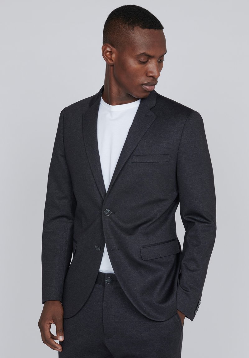 Chaqueta de traje ajustada color gris oscuro con un corte slim, cierre de un solo botón y solapas con muesca. Textura suave con un patrón sutil.