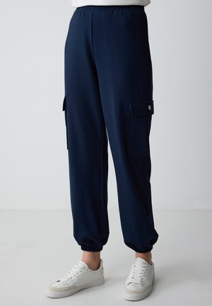 Navy blue cargo pants with an elastic waistband, tapered cuffs, and side pockets. Fabric appears smooth and has a lightweight texture.