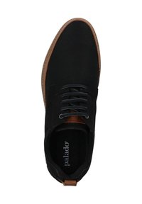 Zapatilla de lona negra con detalles en cuero marrón. Cuenta con punta redonda y seis ojetes con cordones oscuros. La plantilla muestra el nombre de la marca "Palado."