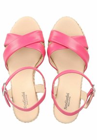 Sandali in pelle rosa con cinghie incrociate, suola piatta e fibbia alla caviglia, che mostrano una texture liscia e una soletta beige neutra.