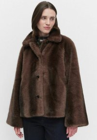 Brązowy płaszcz z sztucznego futra z szerokim kołnierzem, dwiema zapięciami na guziki i luźnymi rękawami. Miękka tekstura i gruby materiał.