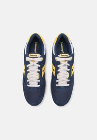 Navy blue sneakers with yellow accents, mesh and suede materials, white laces, and Saucony branding on the tongue and side.