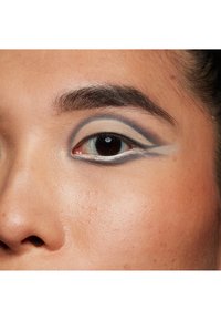 Gros plan sur un œil mettant en avant des fards à paupières superposés dans des teintes beige et bleue, avec un eye-liner bien défini et une texture de peau lisse entourant l'œil.