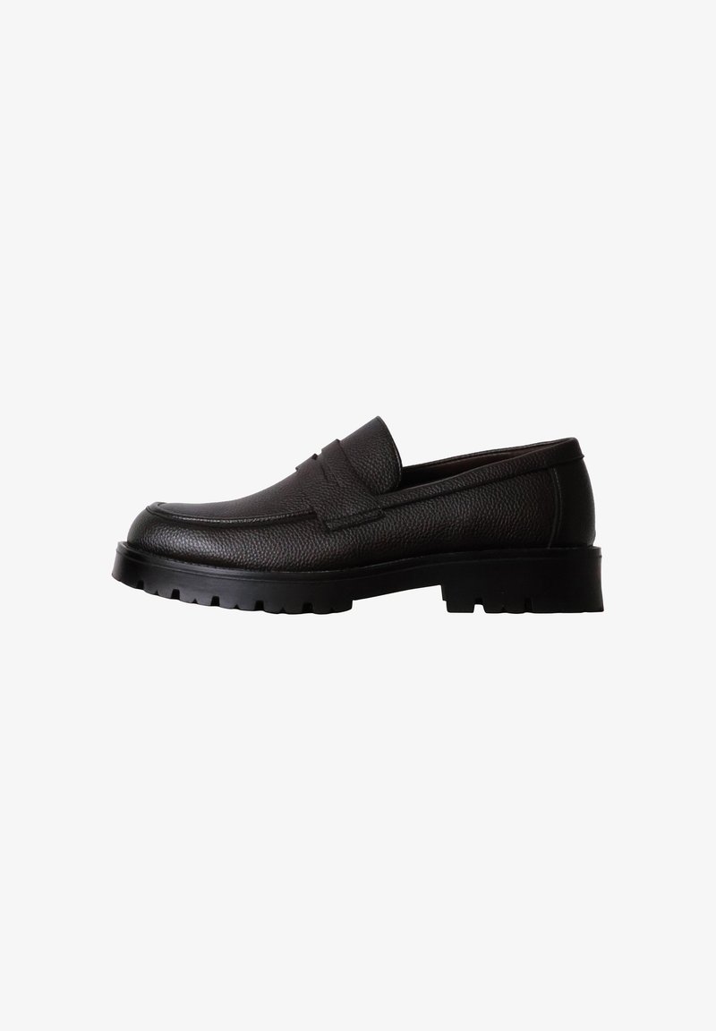 Mocassin en cuir noir avec surface texturée, semelle épaisse à crampons et détail de bride sur le dessus, présenté de côté sur fond blanc.