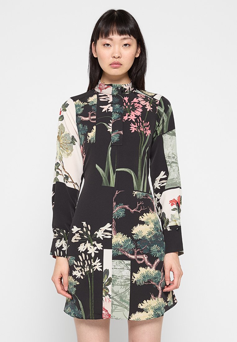 Bloemenpatroon jurk met lange mouwen en een hoge hals, met verschillende botanische afdrukken op een zwarte achtergrond.