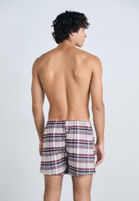 Boxer shorts de algodón a cuadros con cintura elástica. Presentan una mezcla de rayas burdeos, azul marino y blancas. Vista trasera mostrada.