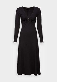 Musta raidoitettu pitkähihaista mekkoa, jossa on syvä V-pääntie ja kierretty yksityiskohta etuosassa. Mekko on lattiatason pituinen ja siinä on virtaava siluetti.