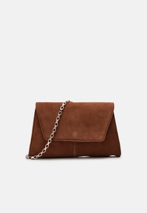Pochette en daim marron avec un rabat triangulaire et une bandoulière chaîne argentée, présentée sur un fond clair uni.