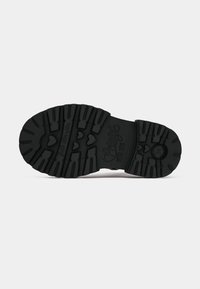 Suela de goma negra con surcos profundos, que presenta un patrón de corazones y el logo de "Primigi" en relieve. Superficie texturizada para un mejor agarre y tracción.