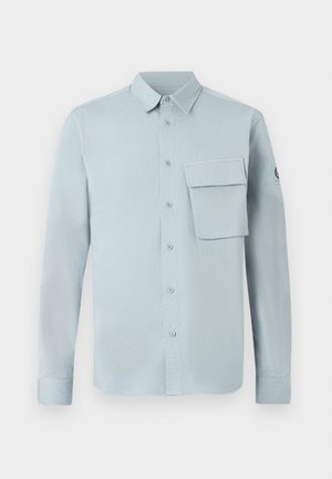 Lyseblå, langærmet skjorte lavet af blødt stof, med knaplukning foran, en brystlomme og et simpelt kravedesign.