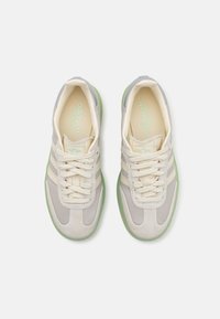 Paire de baskets Adidas beige et grises avec des lacets crème et des semelles en caoutchouc vert clair, vues de dessus sur un fond blanc.