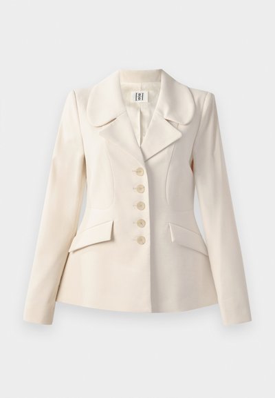 Blazer beige ajustado con grandes solapas, cierre de cinco botones, dos bolsillos frontales y un corte estructurado. Textura de tela suave.