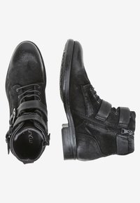 Botas de cuero negras hasta el tobillo con hebillas, cordones y cremallera lateral, mostradas desde vistas superior y lateral sobre un fondo blanco.