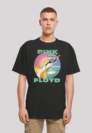 Black cotton t-shirt featuring a graphic print with "PINK FLOYD" text and a stylized image of a hand holding a futuristic device against a colorful background.