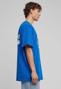 Blå bomulds T-shirt med korte ærmer, afslappet pasform og grafisk design i hvid med farverige accenter på fronten og bagsiden.