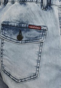 Leren spijkerbroek shorts in lichtblauw met een vervaagd patroon. Voorzien van een achterzak met een rood label en een metalen knoopaccent. Geweven stof.