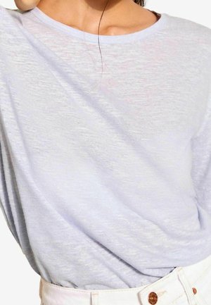 Light blue, short-sleeve top in a soft, textured fabric with a relaxed fit and round neckline, paired with white high-waisted pants.