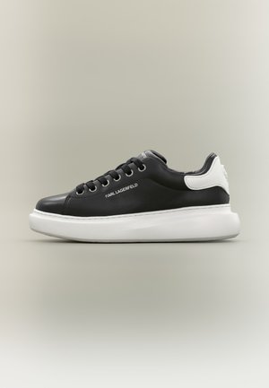 Zwarte lage sneaker met dikke witte zool en hieltab, zwarte veters en "KARL LAGERFELD"-logo aan de zijkant.