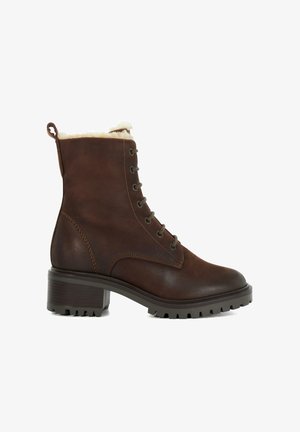 Bottine en cuir marron avec une doublure en fausse fourrure, devant lacé et talon épais. Présente des détails texturés et une semelle robuste pour une meilleure adhérence.