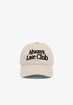 Beige baseballcaps med svart brodert tekst "Always Late Club" plassert midt på frontpanelet mot en hvit bakgrunn.