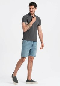 Šedé polo tričko, světle modré denimové kraťasy, šedé nazouvací boty. Krátké rukávy, přiléhavý střih, decentní logo na hrudi.