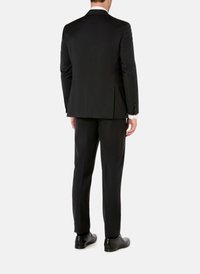 Schwarzer Maßanzug mit einem klaren Design, ausgestattet mit einem Schlitz hinten, glattem Stoff und kombiniert mit schwarzen Schuhen.