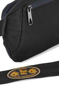 Borsa nera in tessuto con una superficie testurizzata, dotata di una cerniera blu e di un patch che mostra i loghi "PUMA" e "SONIC THE HEDGEHOG" in oro.