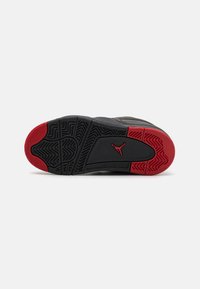 Sole di sneaker nera e rossa con un motivo di battistrada unico e un prominente logo Jumpman rosso. Presenta gomma nera testurizzata e accenti lisci.