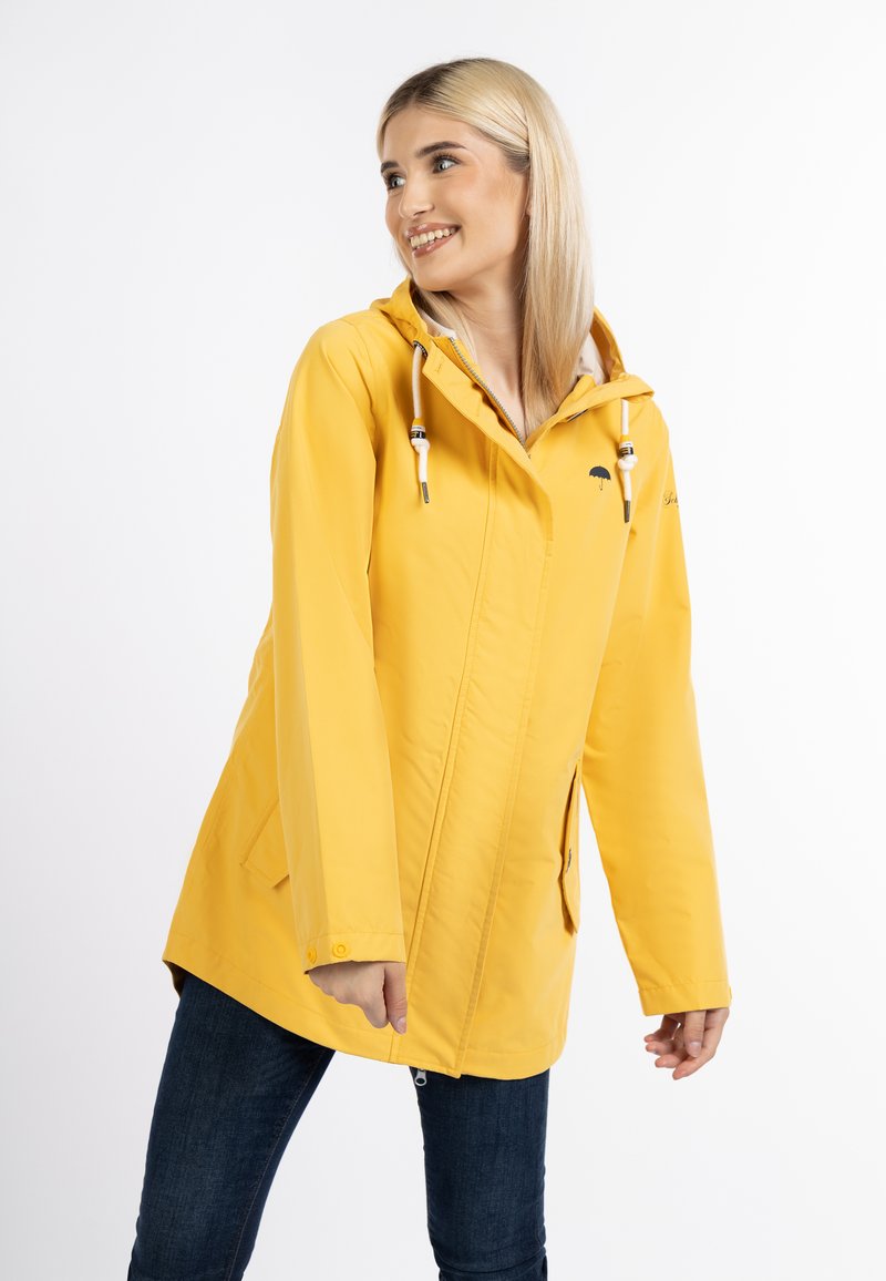 Cappotto impermeabile giallo con cappuccio, realizzato in materiale leggero. Presenta un cordino, zip frontale, due tasche laterali e dettaglio del logo.