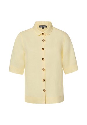 Lichtgele kortärmelig blouse met kraag en zeven bruine schildpadknopen aan de voorkant.