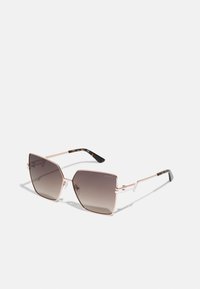 Ochelari de soare hexagonali cu o ramă din metal roz aurie, lentile gri cu un gradient și accente de fâșie de țestoasă pe vârfurile sprijinelor.