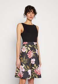 Black sleeveless bodice attached to a flared skirt featuring a floral pattern in pink and green on a dark background.
