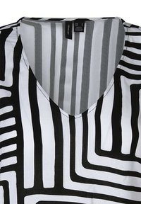 Sort og hvid V-hals top med et geometrisk mønster med varierende linjetykkelser og en glat stofstruktur.