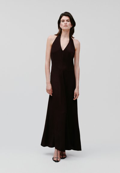 Vestido negro de tirantes halter con un escote en V profundo, falda larga y fluida, tejido suave y diseño minimalista.