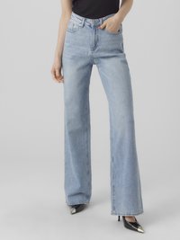 Ljusblå vida jeans tillverkade av denim, med hög midja, femfickorsdesign och rå fåll. Matchas med svarta spetsiga klackskor.