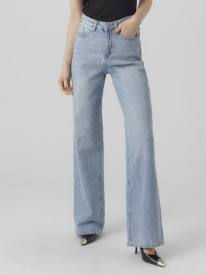 Light blue wide-leg jeans made from denim, featuring a high waist, five-pocket design, and raw hem. Paired with black pointed-toe heels.